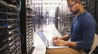 Mixed Race technicians using laptop in computer server room